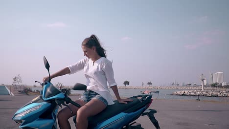 Una-Mujer-Joven-Con-El-Pelo-Largo-Se-Sienta-En-Una-Scooter-Negra-Y-Azul