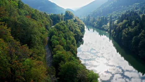 Tiefblauer,-Reflektierender-Flusslauf-Durch-Hügeligen-Wald-Am-Rande-Einer-Kurvenreichen-Straße-Durch-Berglandschaft