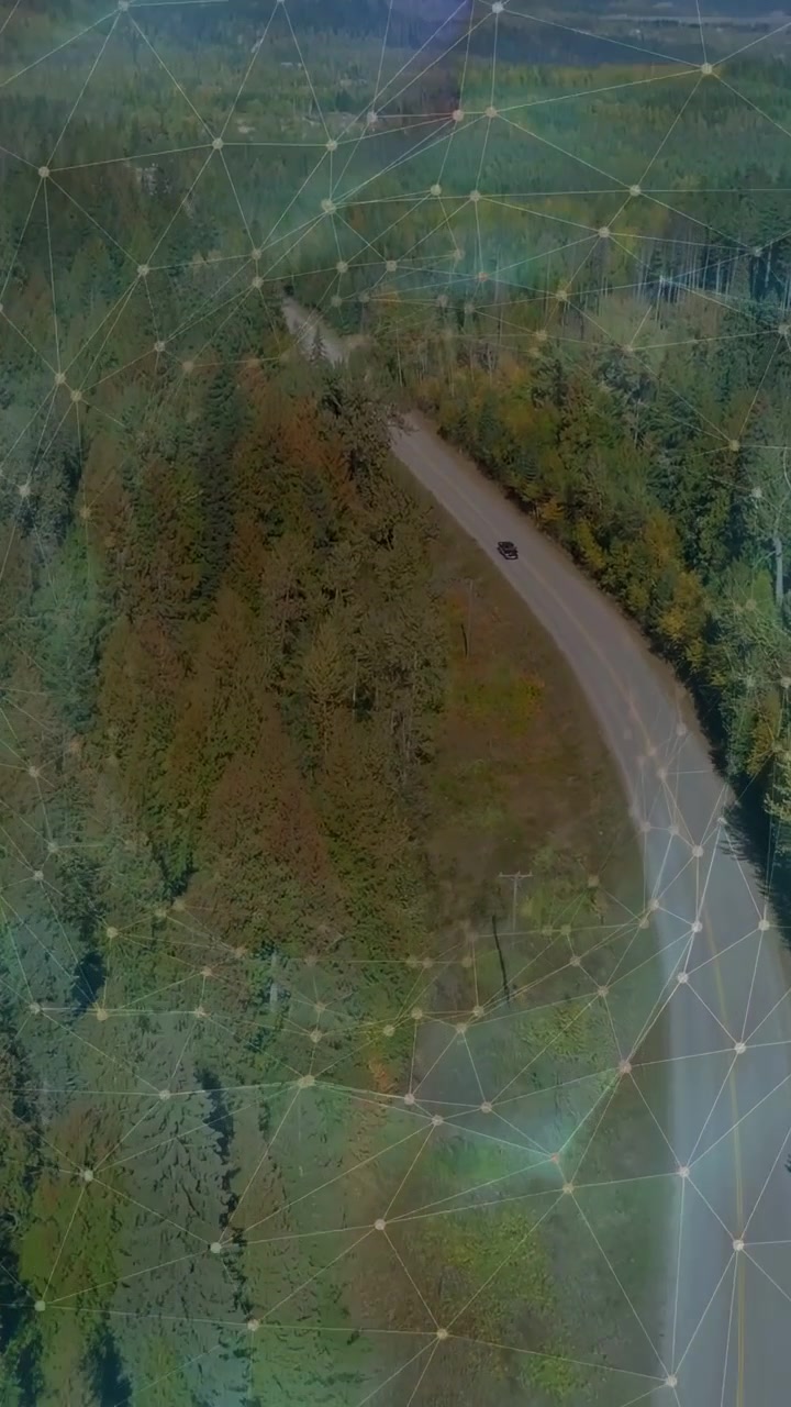 Vertical video: Drone shifting, revealing SUV moving curved road past forest, overlay showing route