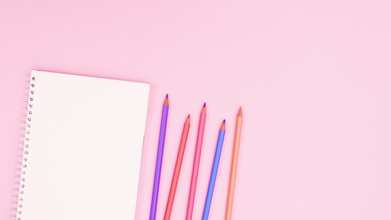 Pastel colored pencils move with notebook on pastel pink theme. Stop motion