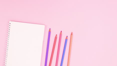 pastel colored pencils move with notebook on pastel pink theme. stop motion