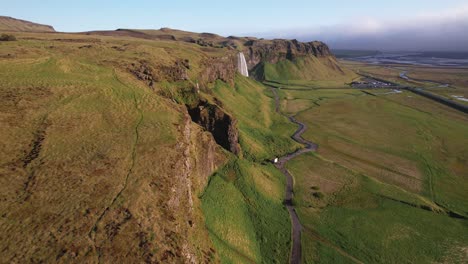 vista aérea de majestuosas cascadas en el exuberante paisaje verde de islandia con río serpenteante y cielo despejado