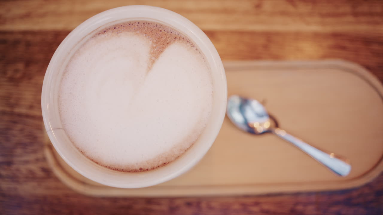 Vista dall'alto di un cappuccino con schiuma di latte cremosa servito su un tavolo di legno