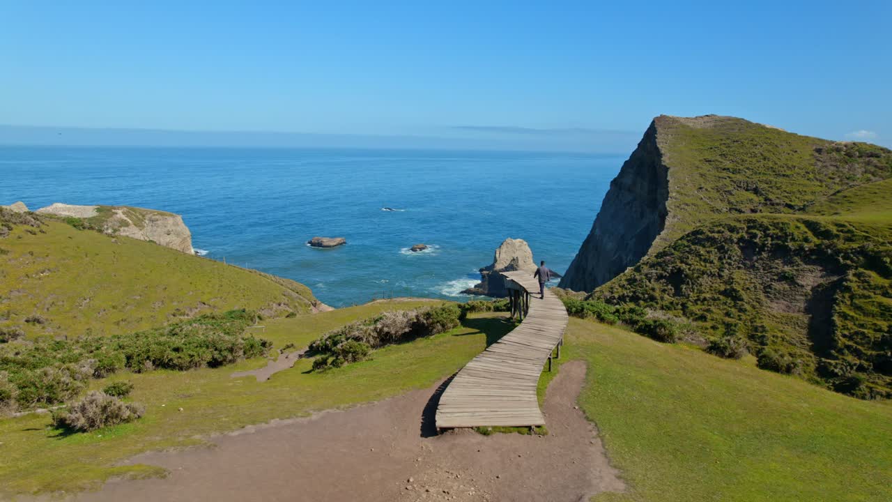 Panoramic orbit flyover of a person walking on the pier of souls in Cucao, Chiloe