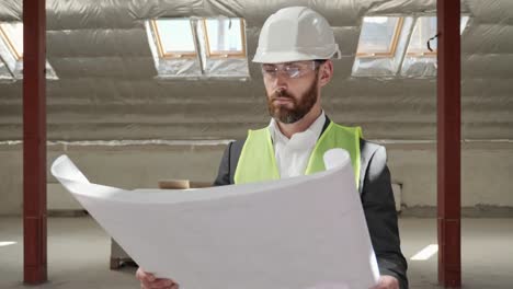 thoughtful professional handsome engineer architect examining blueprint in empty real estate. portrait of serious male expert in helmet thinking planning construction building project. engineering.