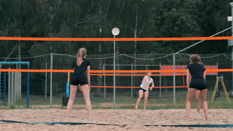 Junge-Frau-Spielt-In-Einer-Mannschaft-Volleyball-Am-Strand-Und-Führt-Einen-Angriff-Durch,-Indem-Sie-Den-Ball-Schlägt.-Mädchen-Schlägt-In-Zeitlupe-Den-Ball-Und-Führt-Einen-Angriff-Durch-Das-Netz-Aus.