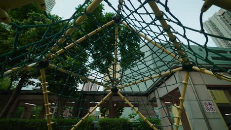 a cinematic pushback shot of a net in a playground in the morning high rise buildings and green trees are at the background