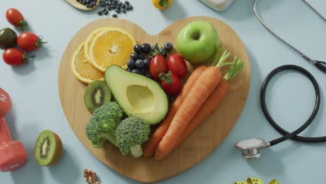 video de frutas y verduras frescas en una tabla de madera en forma de corazón y un estetoscopio