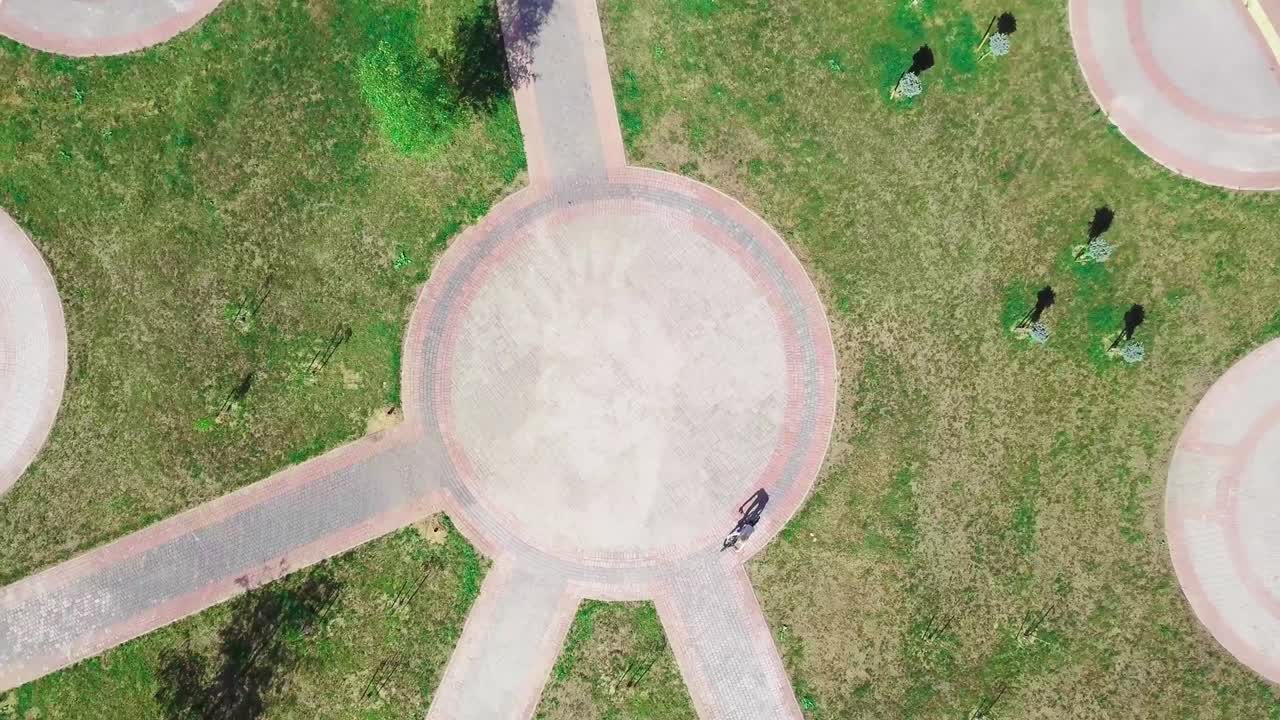 верхний вид женщины на велосипеде, едущей на велосипеде по круговой дороге в городском парке.