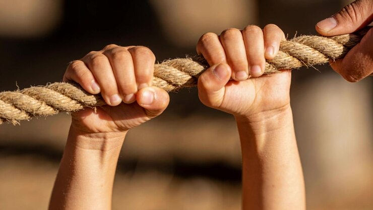 Grasping child hands tightening grip after adult hand contact to steady thick rope at play area