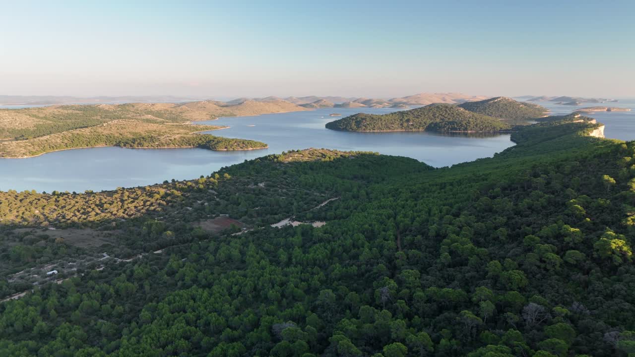 Drone glides over Telascica’s forest and bays, flying towards Kornati islands in golden sunset light