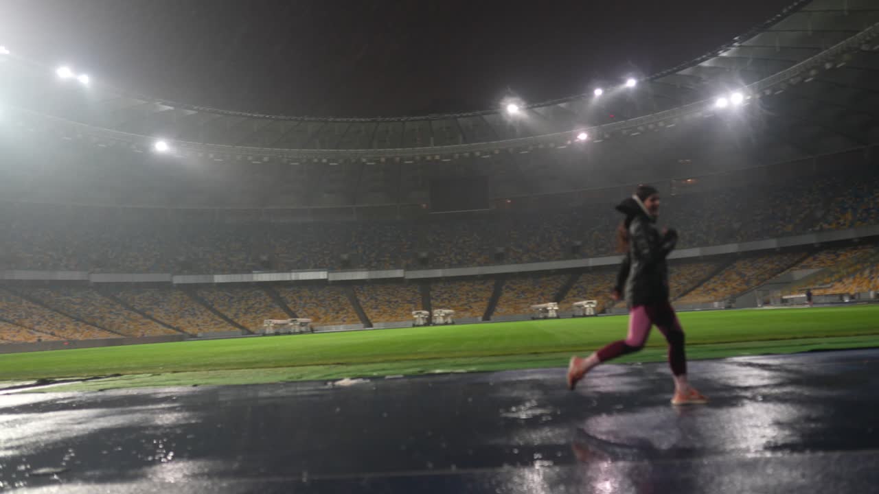 밤 에 비 가 내리는 경기장 에서 운동 선수 의 훈련