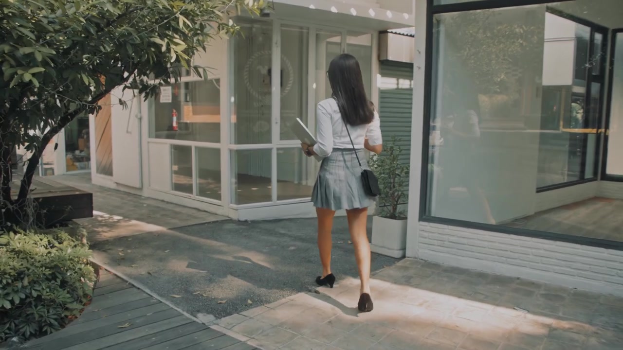 Jovem mulher profissional caminhando do lado de fora de um edifício de escritórios moderno