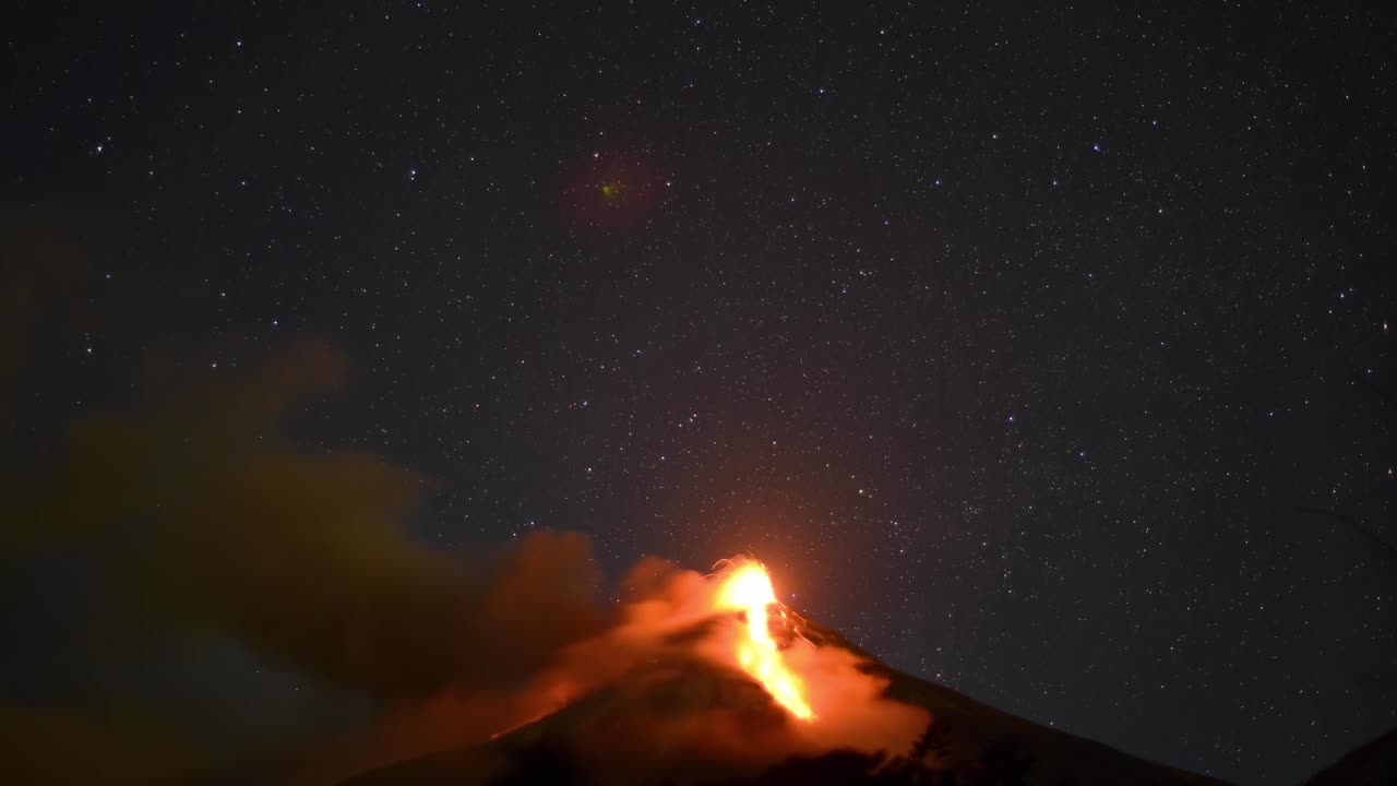 안티구아 과테말라의 파고 화산 (fuego volcano in antigua guatemala) 이 밤에 분출하고 있으며, 배경에는 별들이 움직이고 있다.
