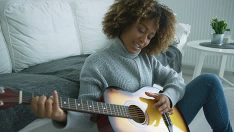 young woman playing guitar at home