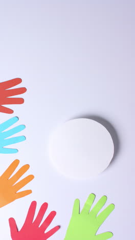 Vertical video of hands around circle made of colourful paper on white background with copy space