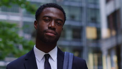 Portrait-Of-Confident-Young-Businessman-Wearing-Suit-Standing-Outside-Offices-In-The-Financial-District-Of-The-City-Of-London-UK