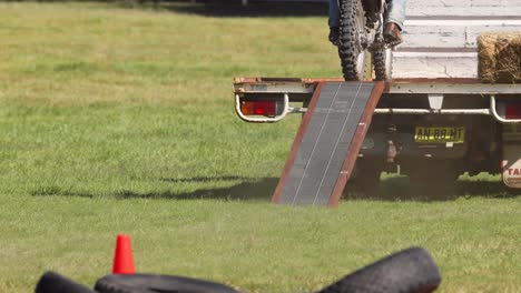 motorcyclist jumps over trailer in grassy field