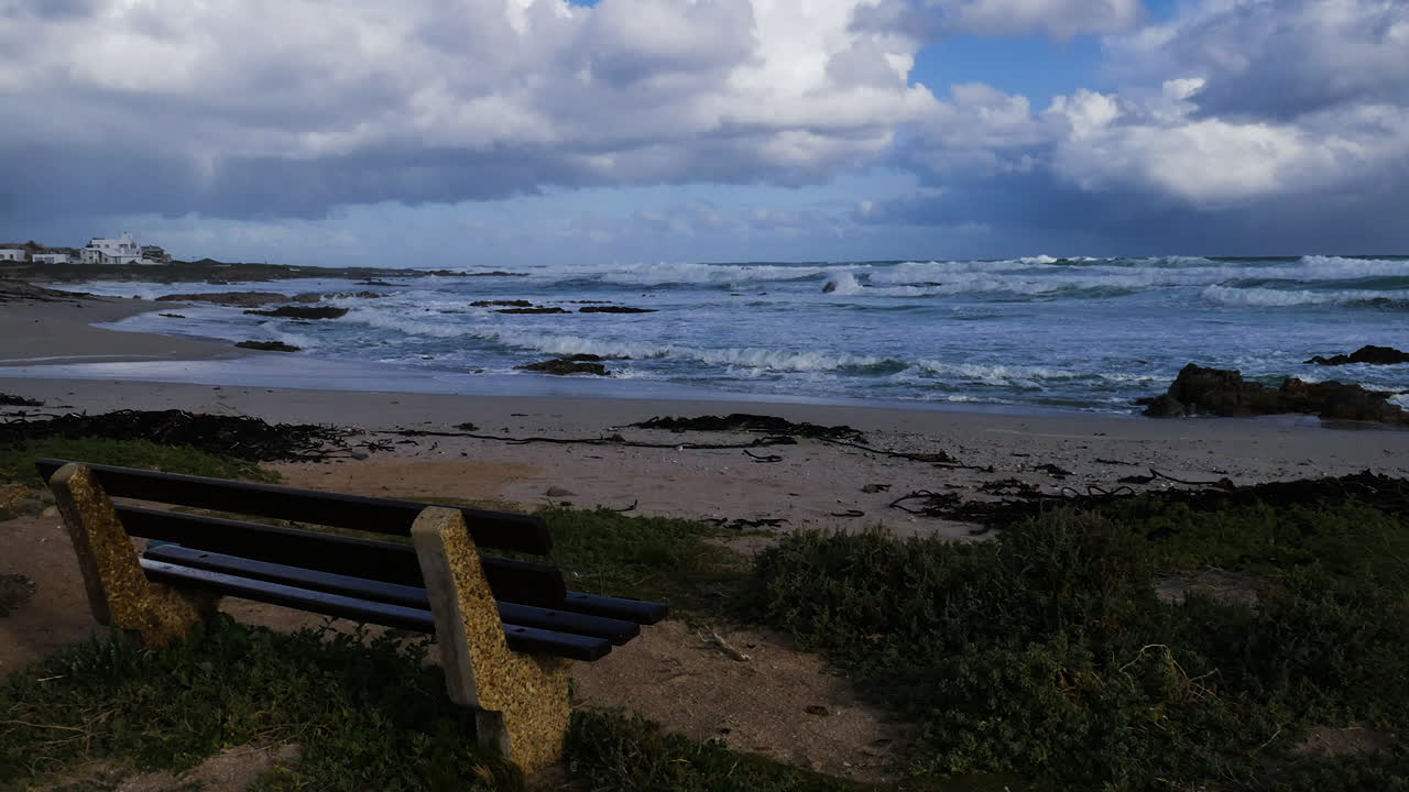 timelapse - 프레임을 가로질러 이동하는 구름, 전경에 벤치가 있는 바다 너머 전망