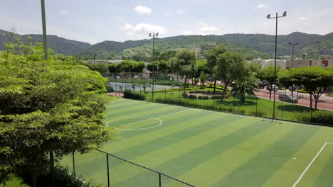 disparo revelador subiendo en 4k de mini campo de fútbol vacío rodeado de parque y árboles y casas en una comunidad cerrada fuera de la ciudad de guayaquil, ecuador