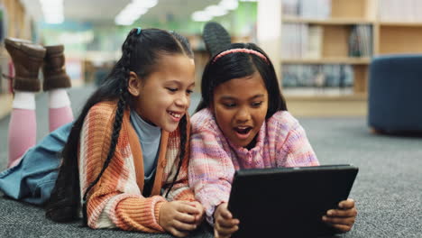 two girls using a tablet in a library