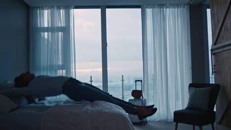 happy young woman jumping on bed resting after successful travel journey enjoying independent lifestyle freedom in hotel room