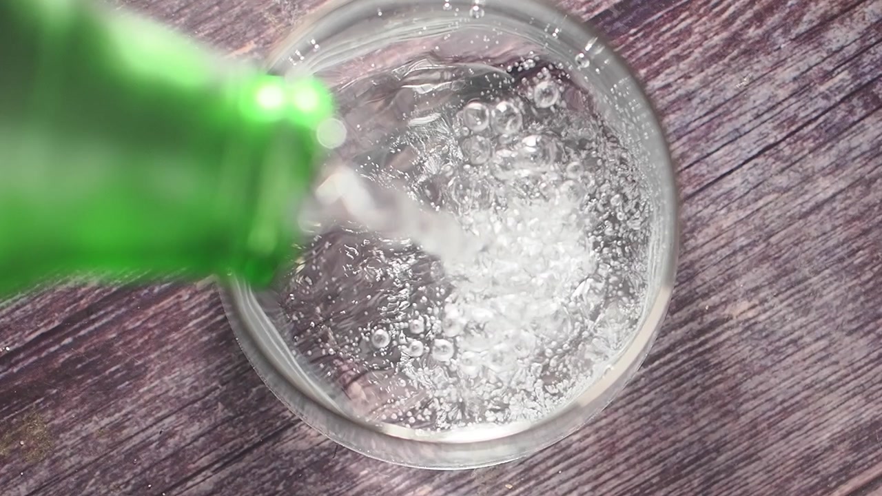 Refreshing Sparkling Water Poured from Green Bottle into Glass