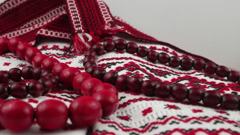 red beads, decorative belt and viburnum twigs on embroidered fabric