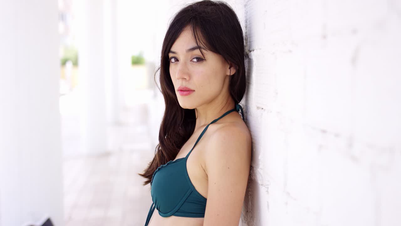 una mujer hermosa apoyándose en la pared.