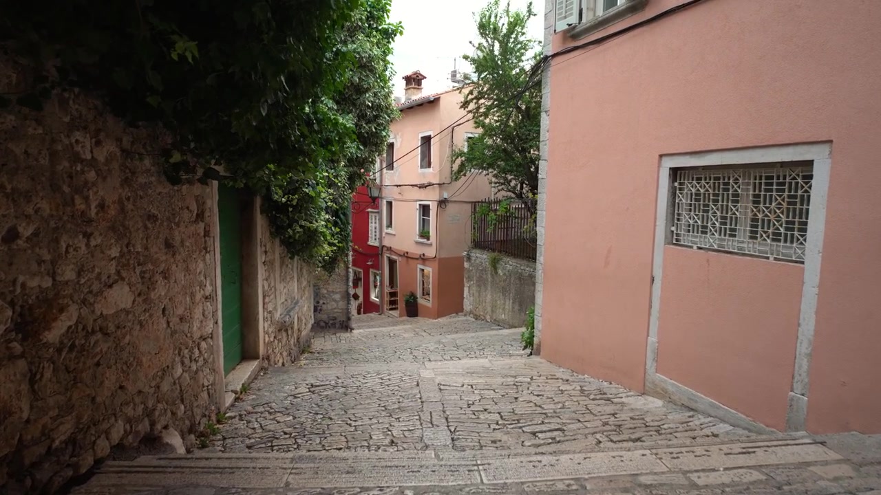 Calle histórica del casco antiguo en Rovinj, Croacia. Fachadas de piedra desgastadas, paredes rústicas, callejón empedrado
