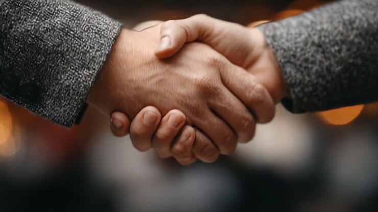 Primer plano de un apretón de manos entre dos individuos, simbolizando acuerdo y colaboración en un contexto de negocios o personal, mostrando confianza y asociación