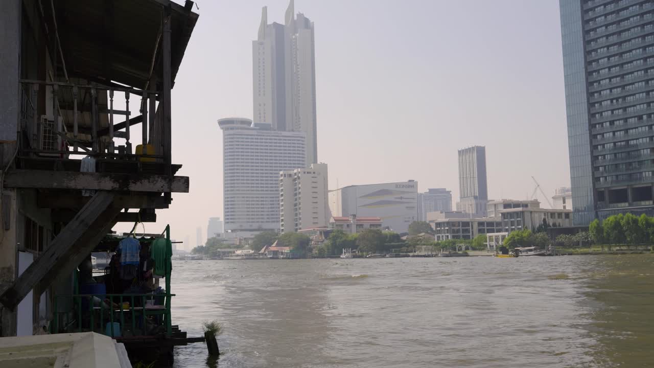 Juxtaposition over modern Bangkok and poor people housing next to river