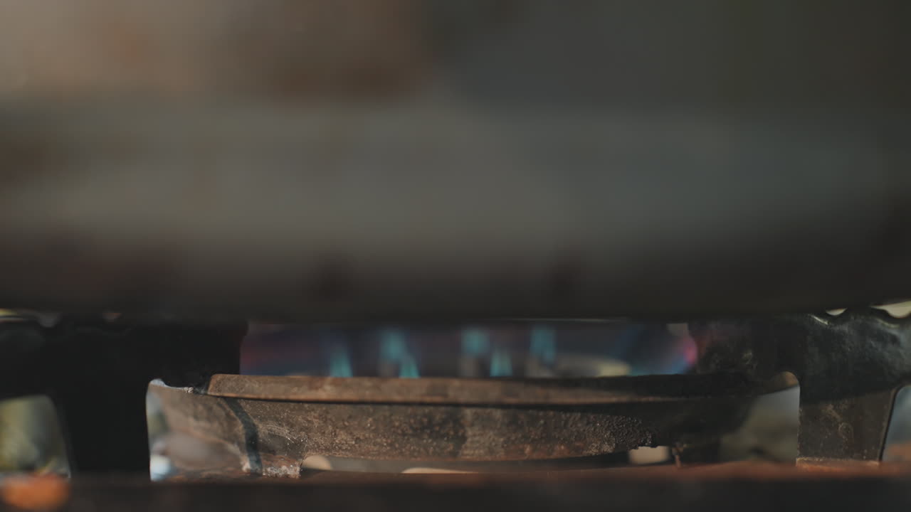 Lavvinkel campingbrænder med brølende blå flamme under tung pande, intens varme og sydende, skumrings-vildmarkskogeatmosfære, brændstofbeholderens ydeevne, robust udendørs madlavning i guide-stil.
