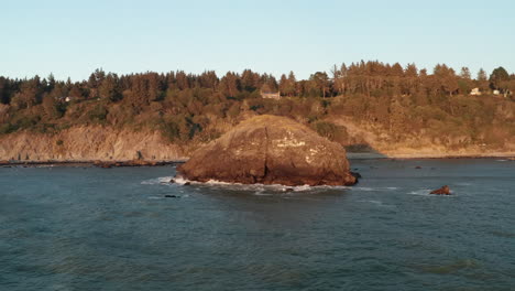 aerial orbit of a large rocky outcrop on the california coastline at sunset