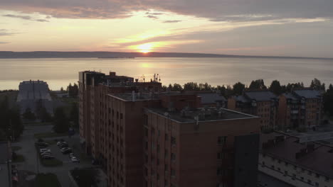 drone approaching high-rise buildings on the lake at dawn in summer