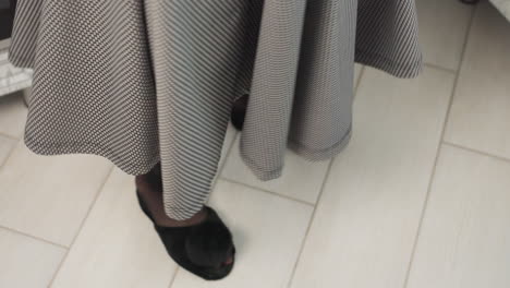 joyful elegant woman wearing stylish plaid gown and pantyhose happily dancing in kitchen while fabric gracefully floats around, expressing cheerful mood in bright modern home interior