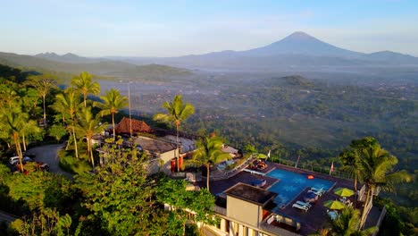 eco-resort with swimming pool and volcano in background in the jungle of indonesia at sunset