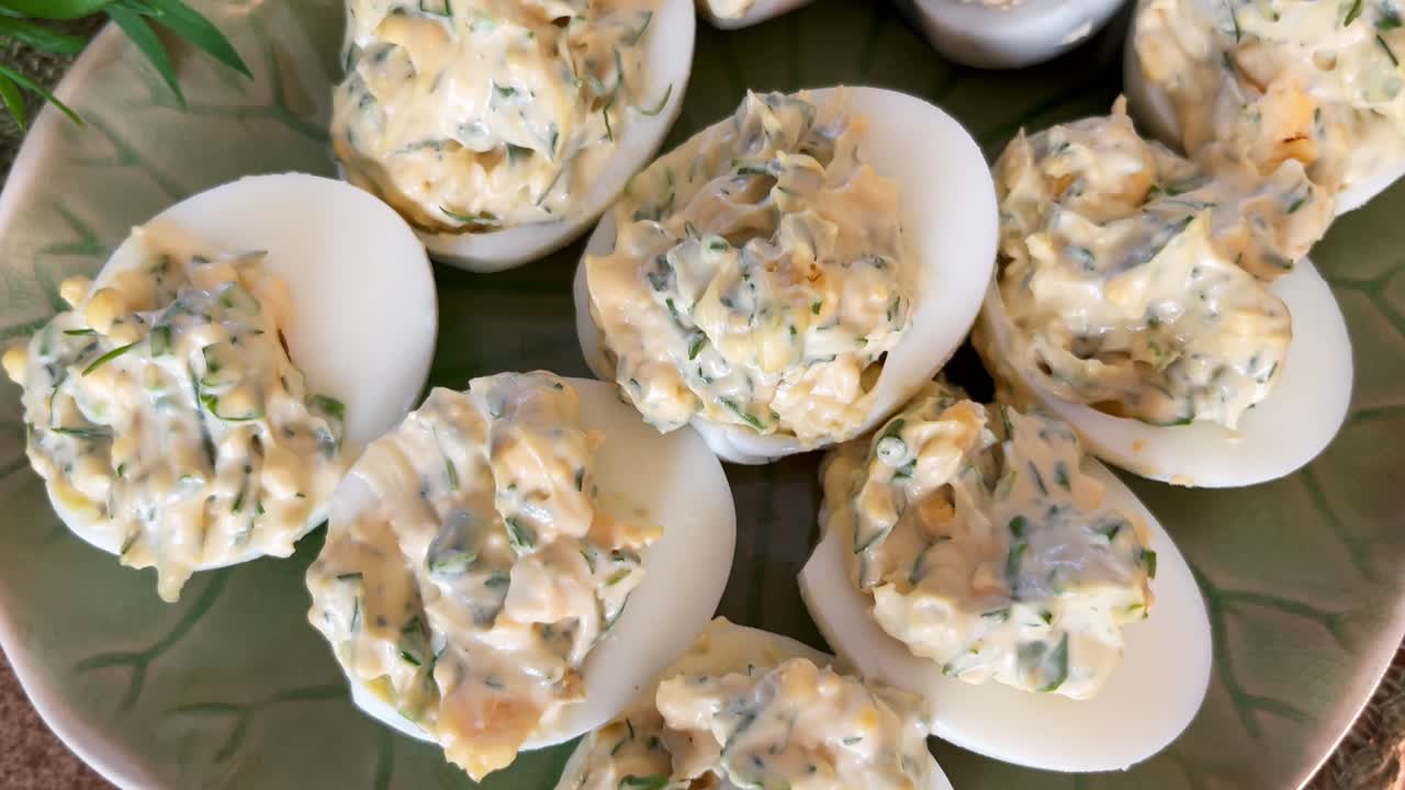 Close-up of creamy deviled eggs on a serving platter, highlighting herb-filled topping and smooth whites in a homemade appetizer presentation