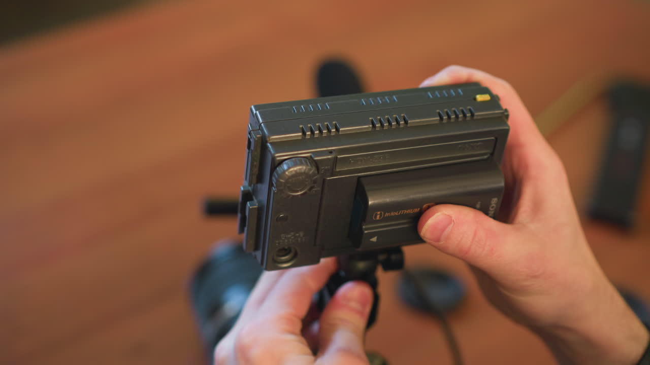 close-up shot of person adjusting camera equipment, mounting microphone on camera rig. hands setting up video production gear for professional shoot. focus on camera, microphone, audio gear