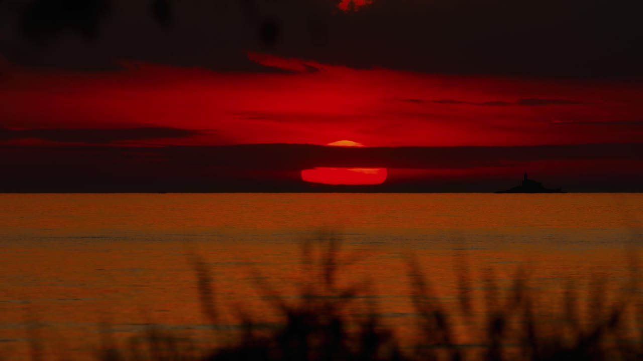 Vibrant sunset light painting clouds and sea reflections in Istria, Croatia with a big red sun