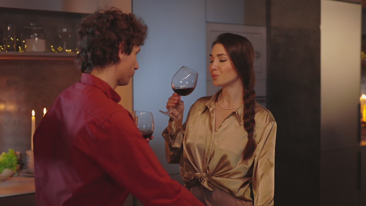 A couple enjoys a romantic evening with red wine in their modern kitchen