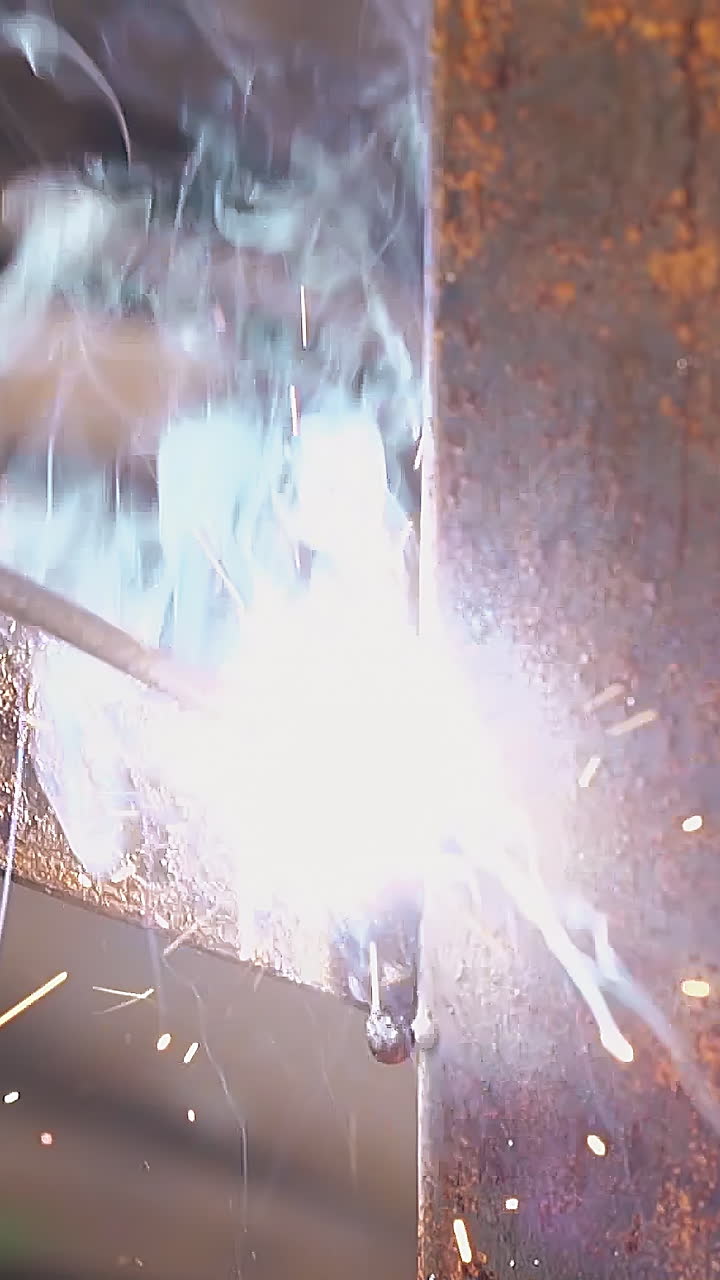 slow motion closeup man hand holds welding tool using for fixing plank to metal fence pole on day