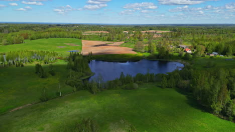 Vast-green-panorama-nature-park-with-small-pond-and-tiny-settlement,-timelapse