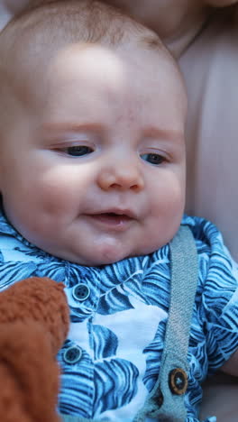 adorable caucasian infant in blue shirt lies on the soft backdrop. fluffy brown teddy is near the kid. close up. vertical video