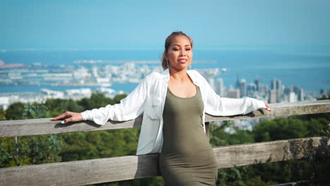 une femme profite d'une vue panoramique sur la ville depuis une balustrade au sommet d'une colline.