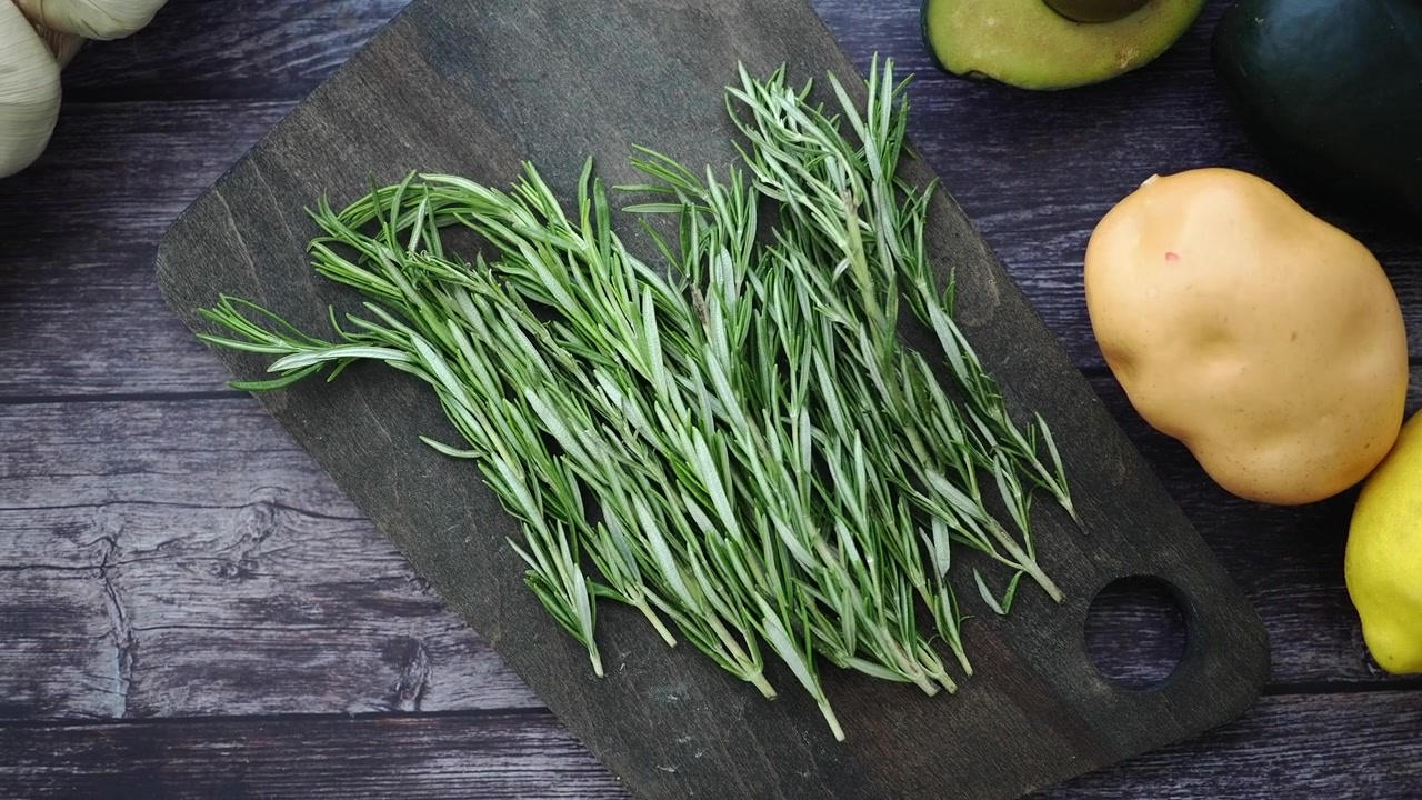 Fresh Rosemary Sprigs on a Wooden Cutting Board with Vegetables