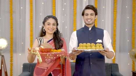 indian couple wishing happy diwali with sweets and pooja thali