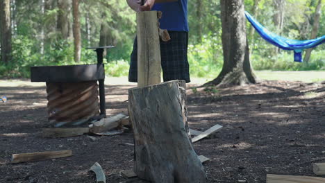 Caucasian man chops wood with an axe, camping in the Canadian wilderness