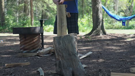 kaukasischer mann hackt holz mit einer axt und zeltet in der kanadischen wildnis