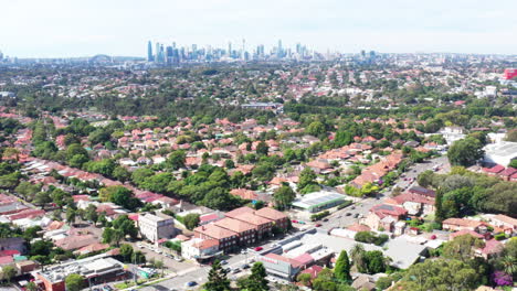 Disparo-Aéreo-De-Un-Dron-Sobrevolando-Casas-Residenciales-Hacia-La-Ciudad-De-Sydney-En-La-Distancia,-Australia